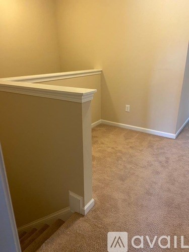 A carpeted room with a wall and a door.