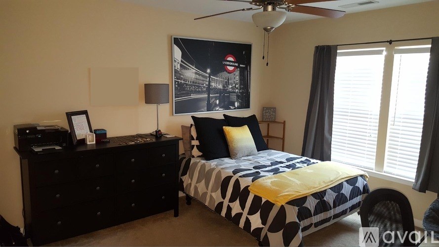 A bedroom with a bed, dresser, and a ceiling fan.