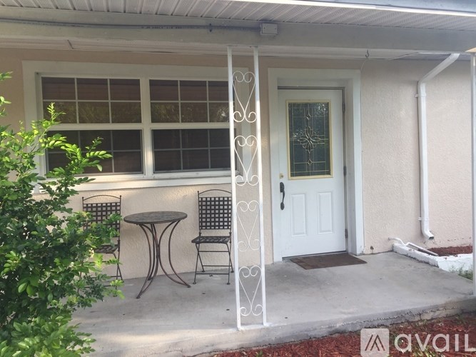 A white door with a glass window above it and a table and chairs outside a house.