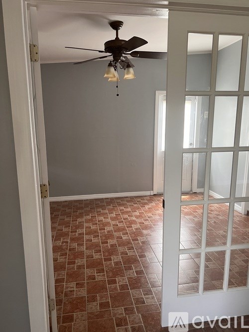 A room with a ceiling fan and tiled floor.