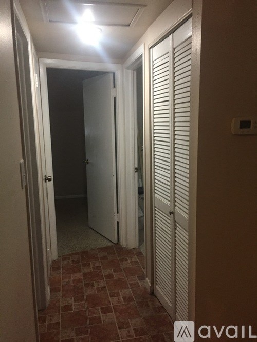 A hallway with a tiled floor and a closed door on the right.