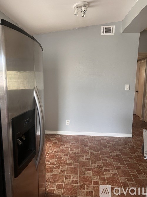 A kitchen with a stainless steel refrigerator and a tiled floor.