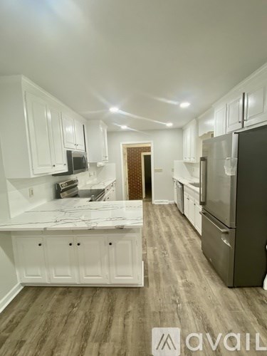 A kitchen with white cabinets and a marble countertop.