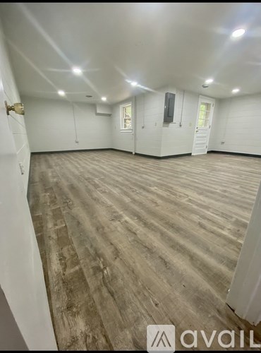 A spacious room with wooden flooring and white walls.