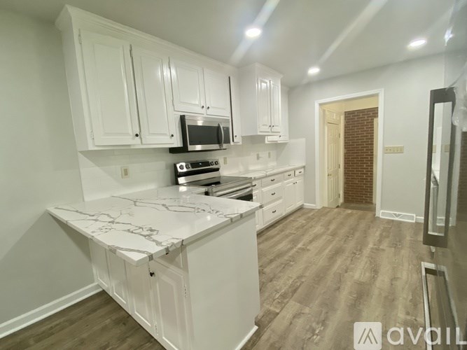 A kitchen with white cabinets and a marble countertop.