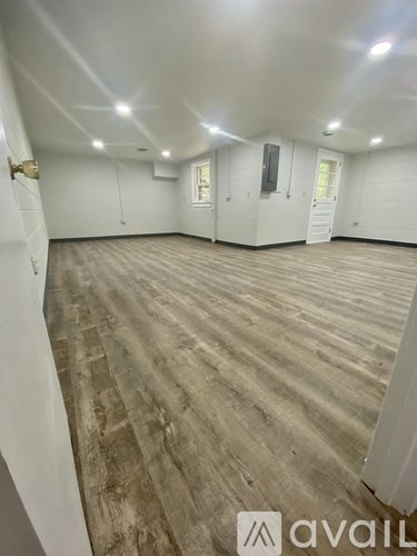 A spacious room with wooden flooring and white walls.