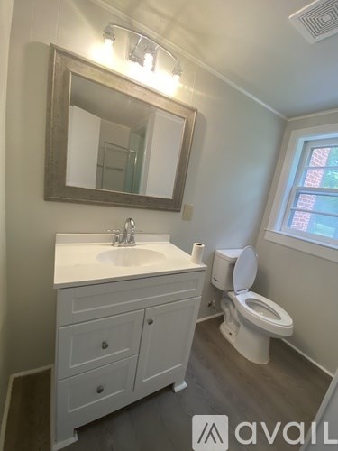 A bathroom with a toilet, sink, and mirror.