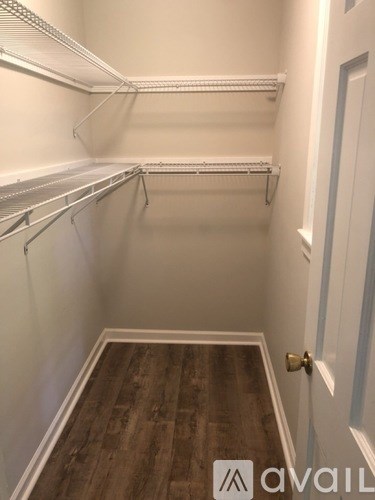 A white closet with wood floors and a white door.
