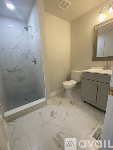 A bathroom with a marble floor and a walk-in shower.