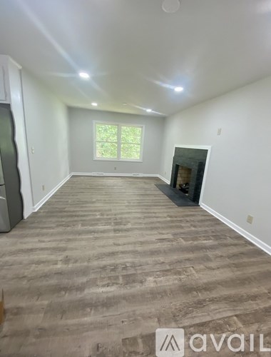 A spacious room with wooden flooring and a window.