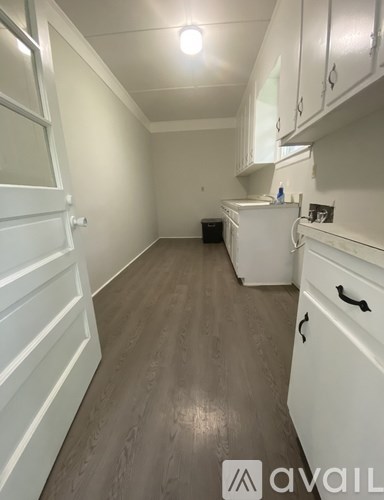 A small kitchen with white appliances and wooden floors.