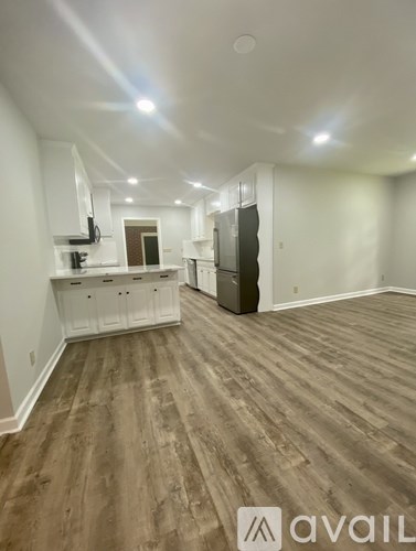 A spacious kitchen with wood flooring and white cabinets.