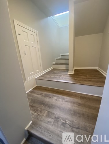 A hallway with a wooden floor and a white door.