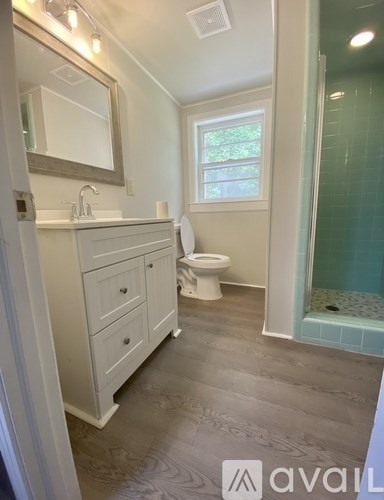 A bathroom with a toilet, sink, and mirror.
