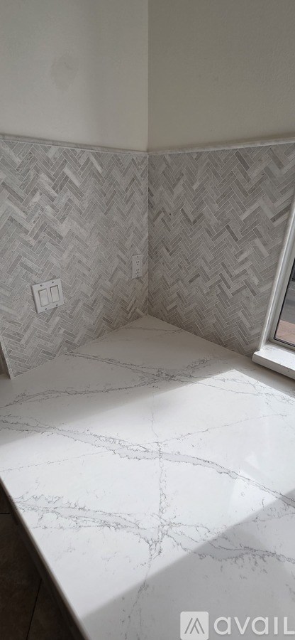 A bathroom with a marble floor and a herringbone patterned wall.