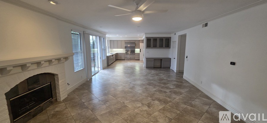 A spacious living room with a fireplace and a kitchen in the background.
