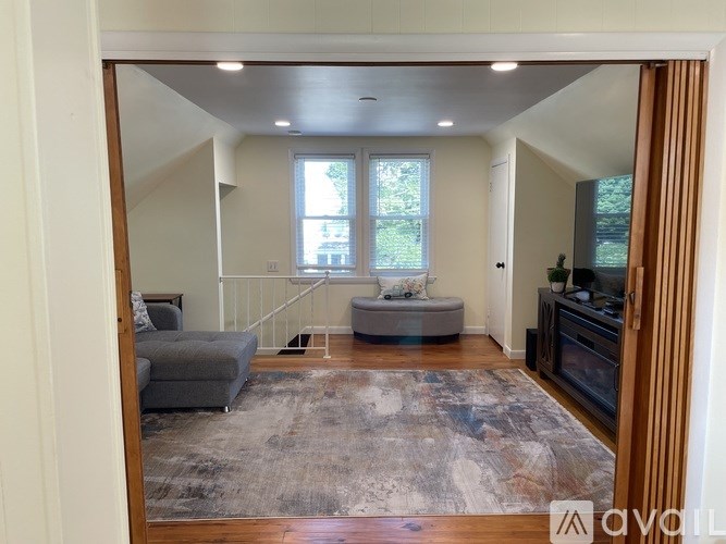 A living room with a grey couch and a rug.