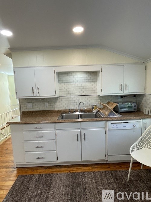 A kitchen with white cabinets and a brown countertop.
