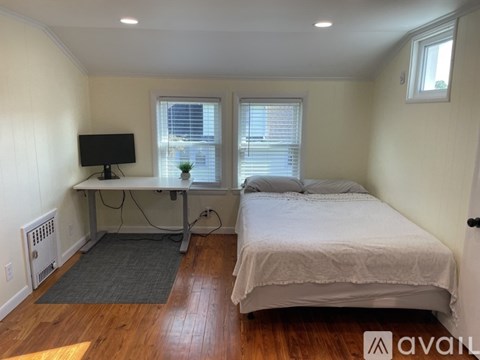 A bedroom with a bed, desk, and window.