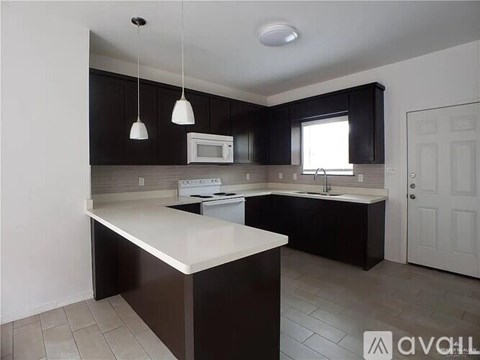 A kitchen with black cabinets and white countertops.