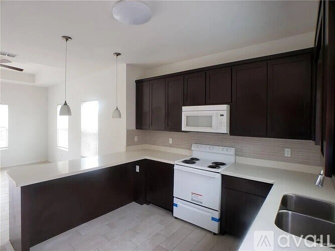 A kitchen with dark brown cabinets and a white stove top oven.