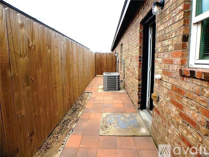 A wooden fence runs along the side of a brick building.