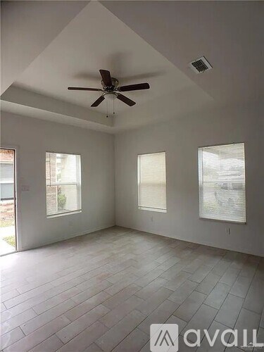 A room with a ceiling fan and three windows.