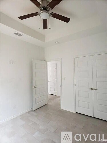 A room with a ceiling fan and three doors.