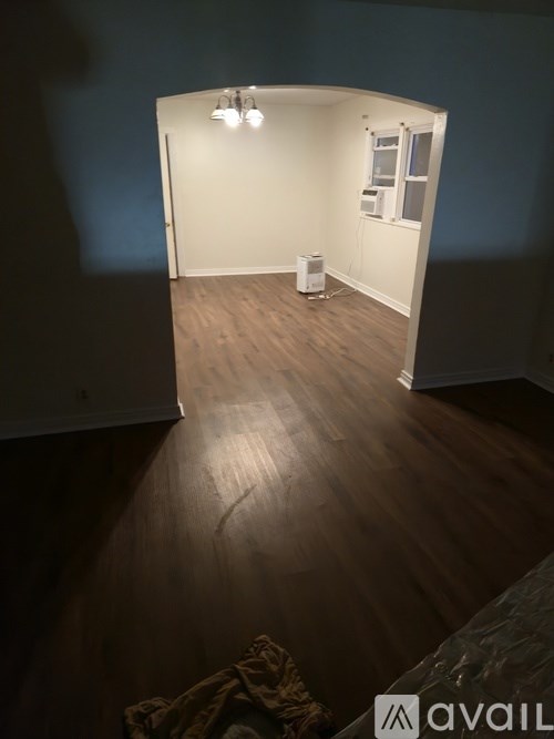 A room with a white door and a window with a white air conditioner unit outside.