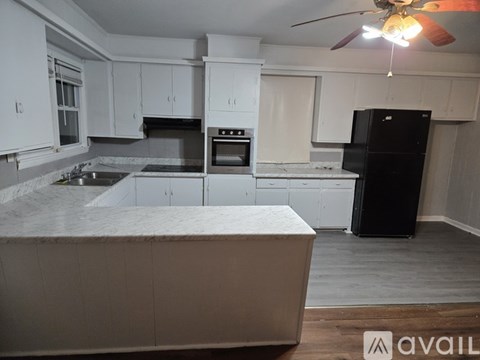 A kitchen with white cabinets and a black refrigerator.