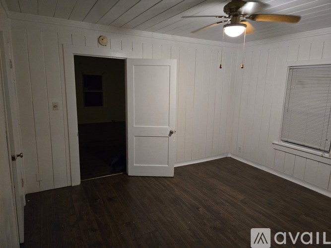 A room with a ceiling fan and a door leading to another room.