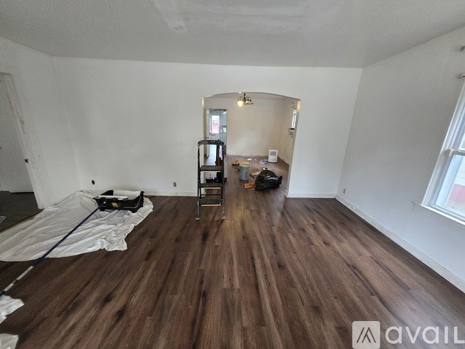 A room with wooden flooring and a ladder is shown.