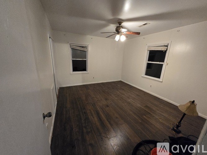 A room with wooden floors and two windows.