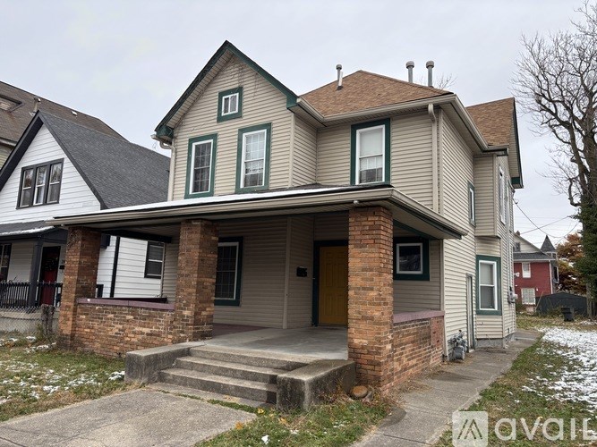A two-story house with a front porch and a brown door.