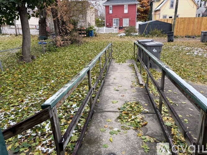 A pathway with a railing on both sides is covered in leaves.