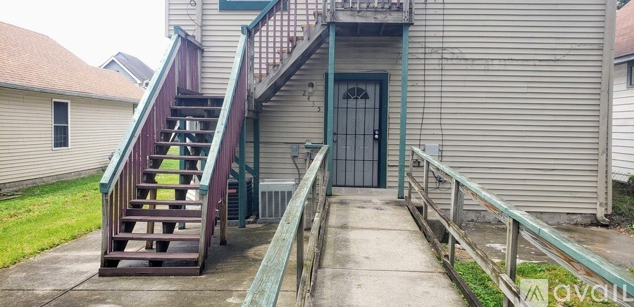 A wooden staircase with a green railing leads to a door.
