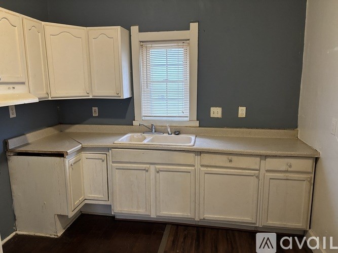 A kitchen with white cabinets and a window above the sink.