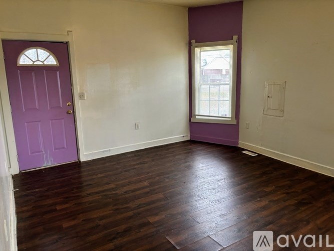 A room with a purple door and wooden floors.