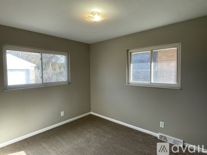 A room with two windows and carpeted floor.