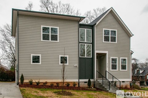 A two-story house with a grey exterior and a black door.