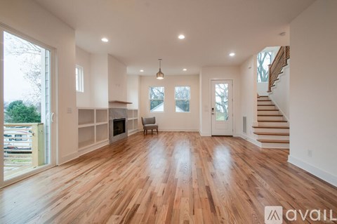 A spacious living room with hardwood floors and a staircase leading to the upper level.