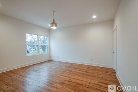 A room with wooden flooring and a pendant light hanging from the ceiling.