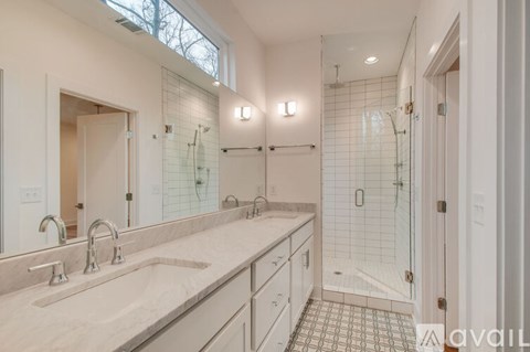 A bathroom with a walk-in shower and double sinks.