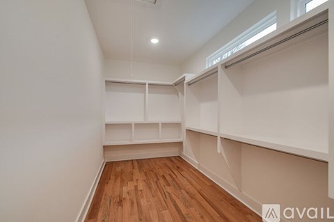 A room with wooden floors and white walls, with a window on the right side.