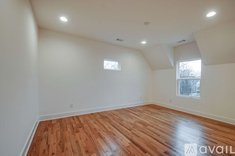 A room with wooden floors and two windows.