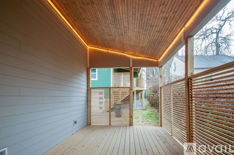 A wooden deck with a roof and a wall on the left side.