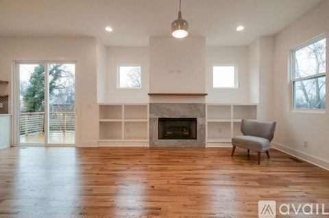 A large, empty room with a fireplace and a chair.