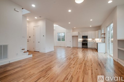A spacious room with wooden floors and white walls.