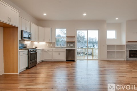 A spacious kitchen with wooden floors and white cabinetry.