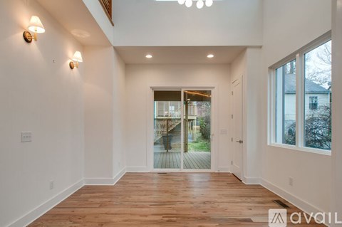 A spacious room with wooden floors and white walls.